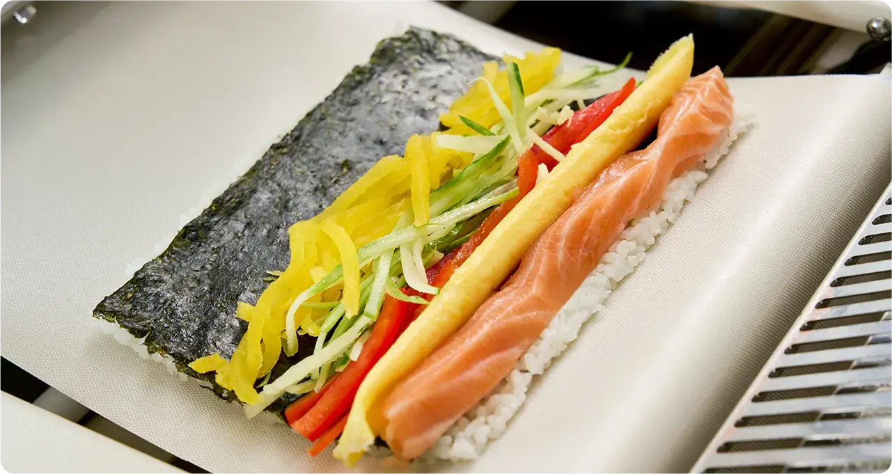 Perfectly rolled assorted kimbap and california rolls made by automatic roller machine